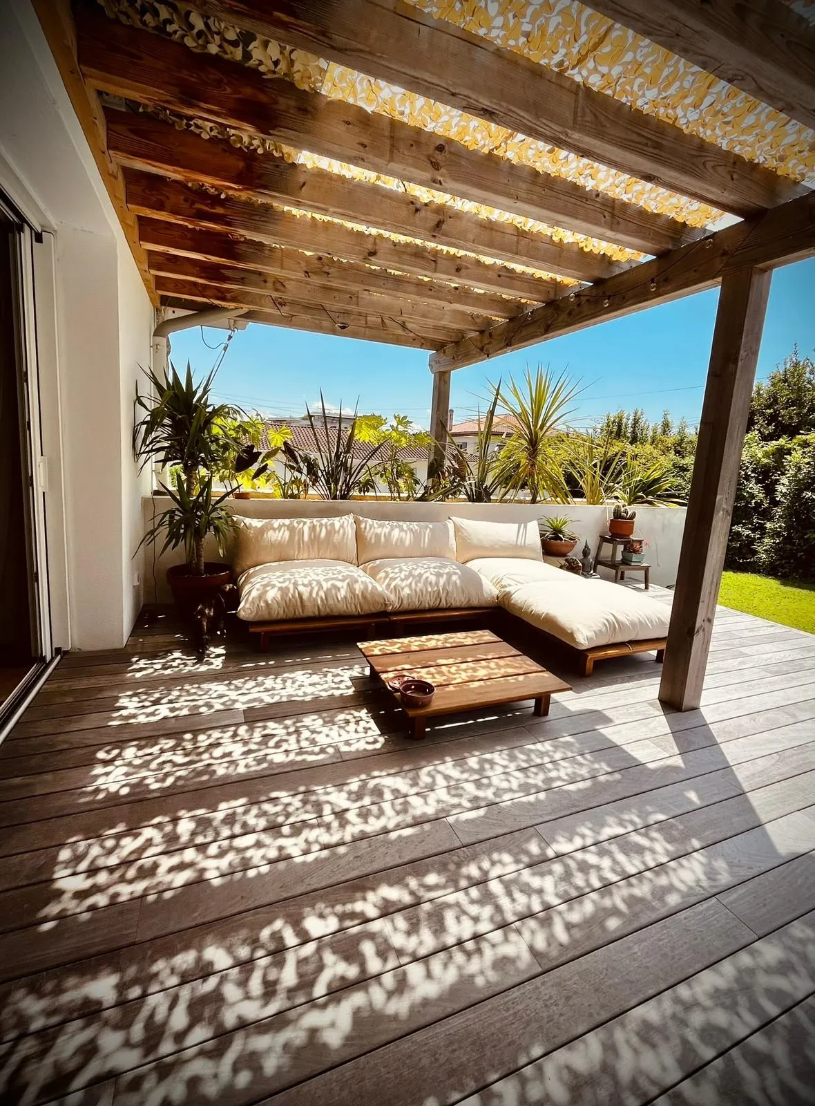 Terrasse en bois sous pergola, aménagée en salon d’extérieur