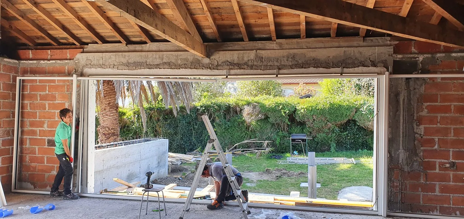 Pose de la baie vitrée de 4 mètres par les compagnons, charpente encore apparente