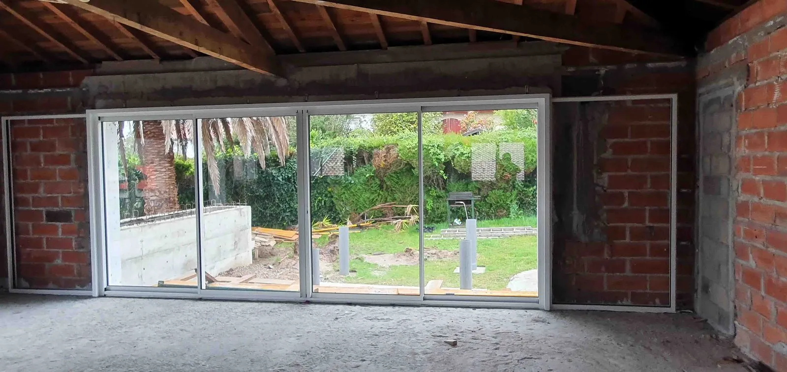 La baie vitrée de 4 mètres posée, vue depuis l’intérieur brut vers le jardin